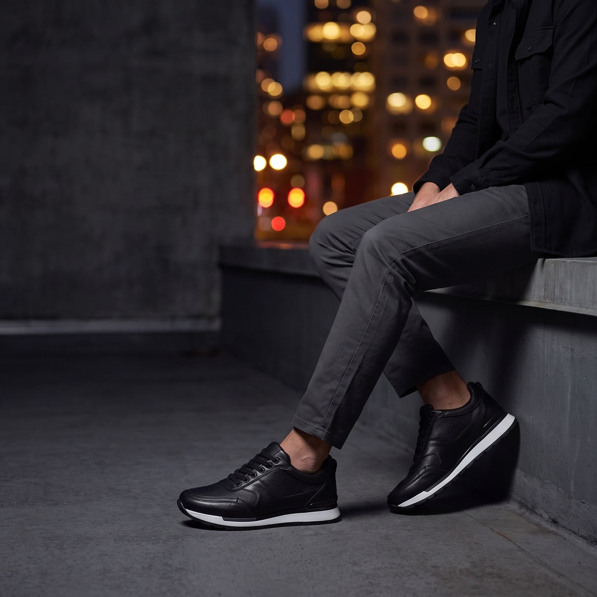 Hombre sentado de noche con tenis Vancouver negro